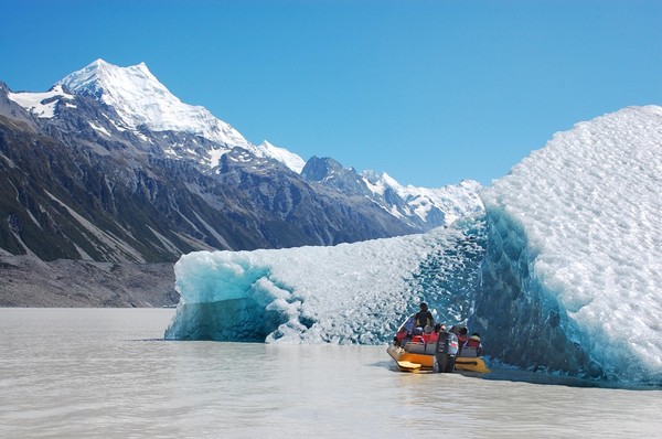 Glacier Explorers visitors view iceberg blue ice with Mount Cook in the distance